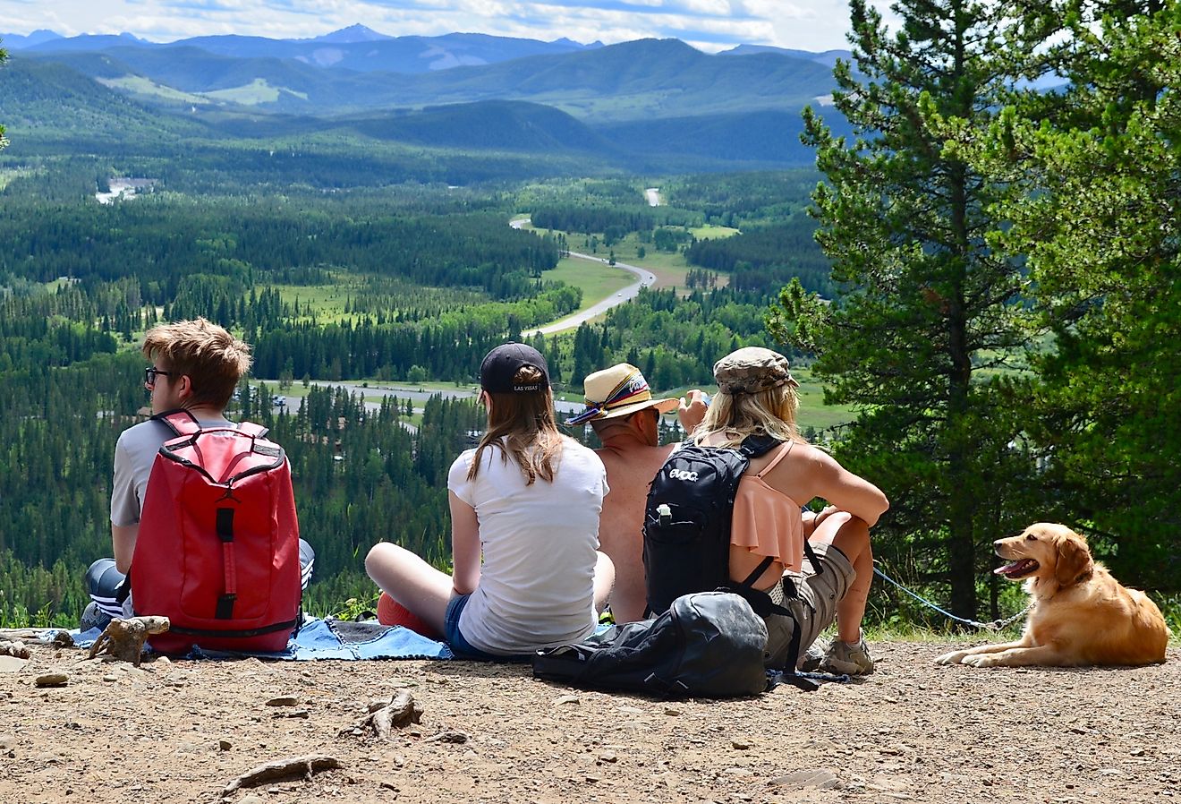 Family with a dog sitting on the ground and enjoying the view from a trail in Bragg Creek, Alberta, Canada. Image credit AIVRAD via Shutterstock