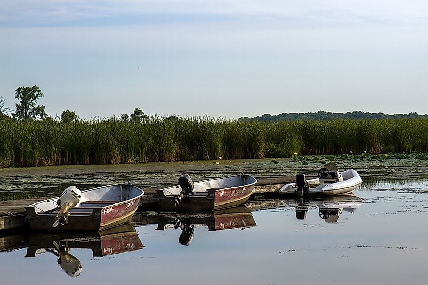 Three motorized fishing boats reflected in the water at dawn in Chain O' Lakes State Park near Antioch, Illinois.