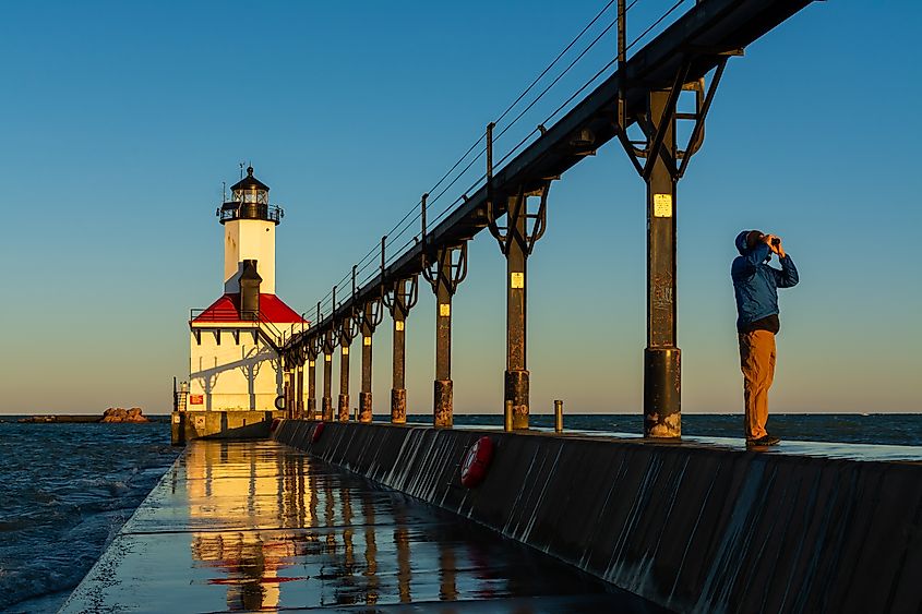 Man with binoculars as the sun rises at Michigan City Lighthouse.