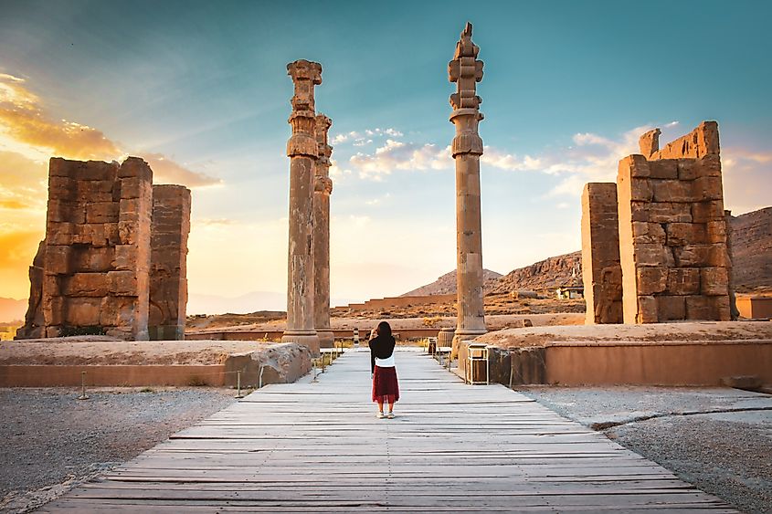 Tourists walk and explore the ancient ruins of Persepolis, a historic Persian city in southern Iran.